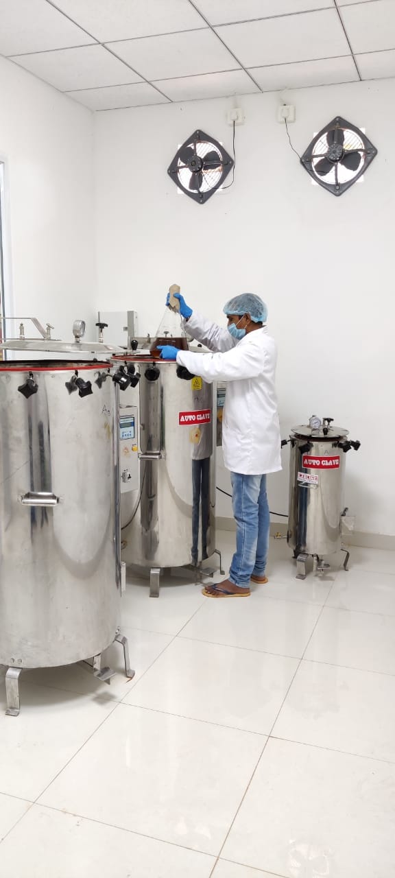 R&D lab technician handling a culture flask beside autoclave vessels